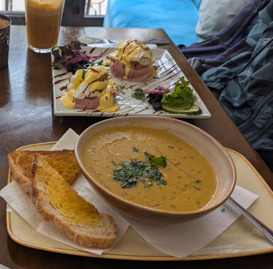 Eggs benedict with a bowl of soup and toast.