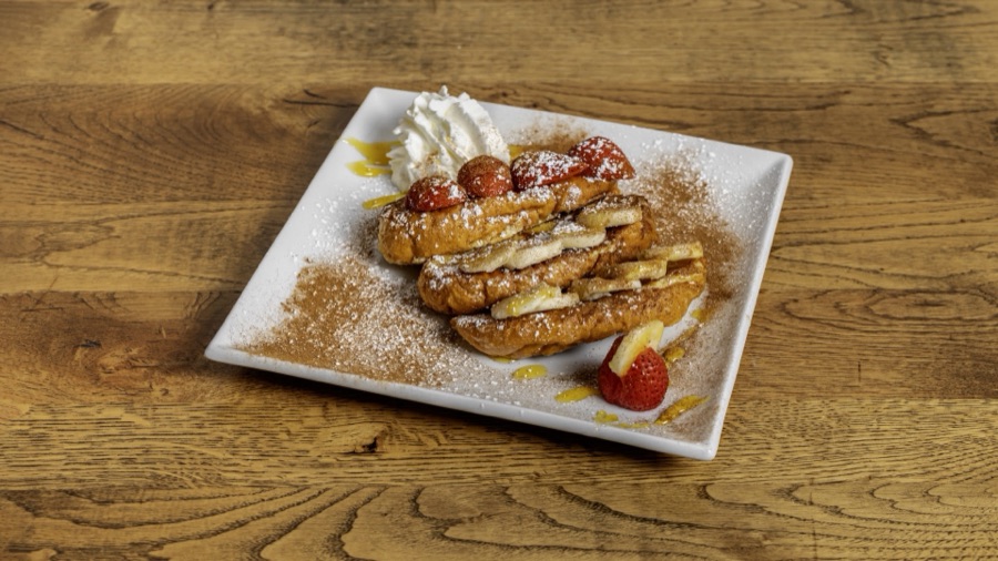 French toast dusted with icing sugar and topped with strawberries and cream.