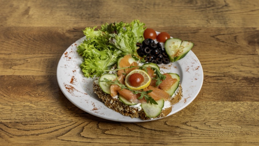 Smoked salmon and cream cheese open sandwich with side salad.